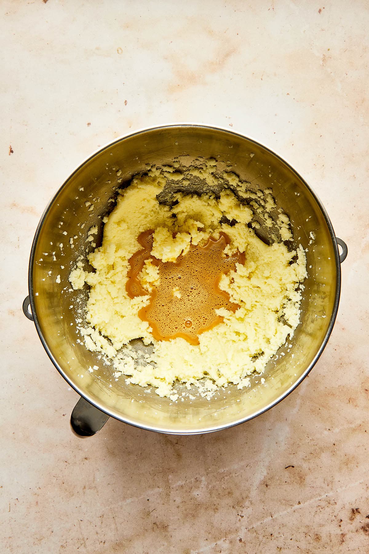 Whisked egg, milk, light coen syrup, and vanilla that's been poured into a metal mixing bowl of whipped butter and sugar.