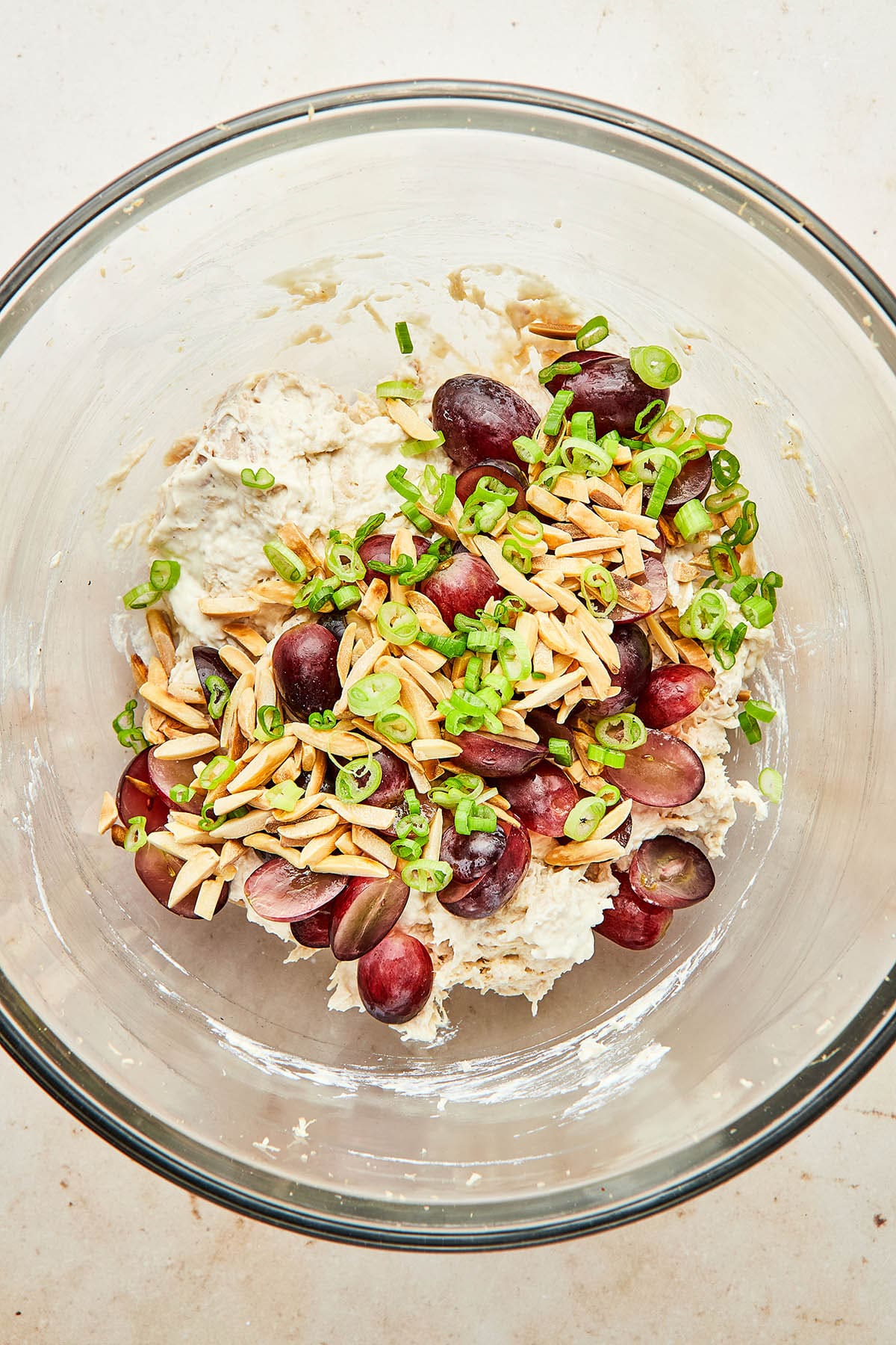 Toasted slivered almonds, red grapes, and sliced green onions about to be mixed into shredded chicken salad.
