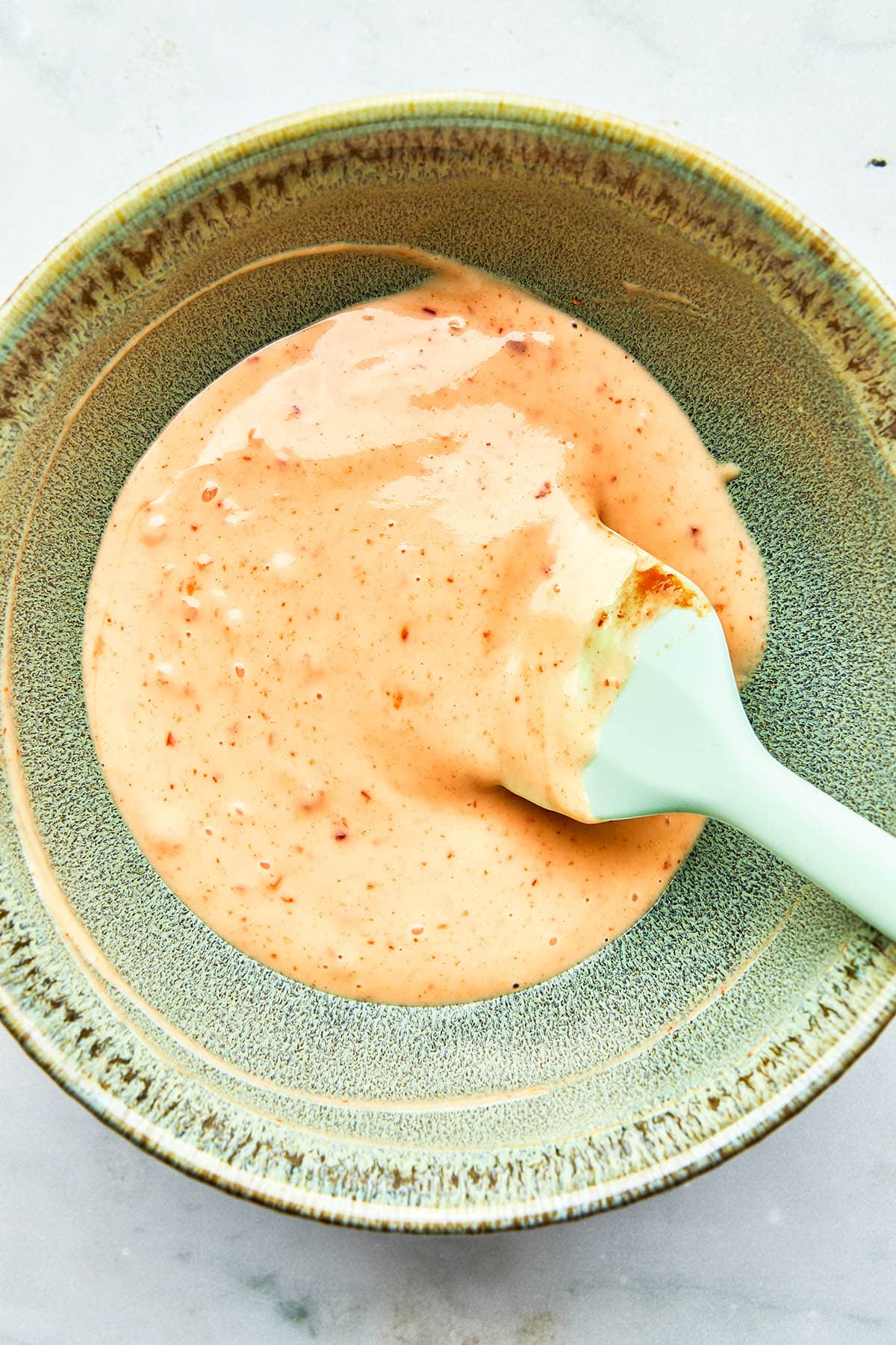 A bowl of homemade shrimp dipping sauce with a small rubber spatula in the bowl.