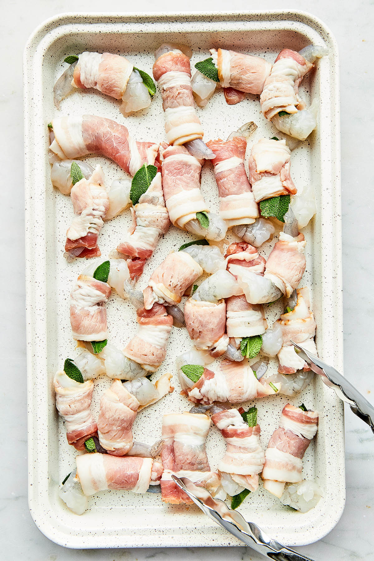 A pan of uncooked bacon wrapped shrimp.