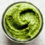 A spoonful of spinach pesto laying on a stone surface.