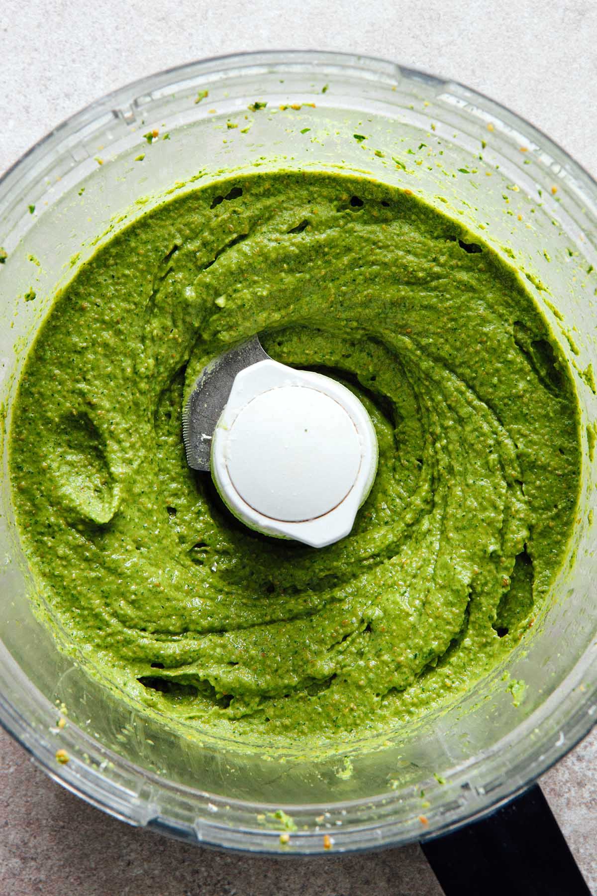 Homemade pesto in the bowl of a food processor after the olive oil has been slowly dribbled in.