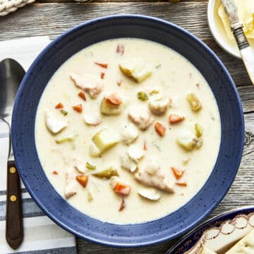 A bowl of Maritime fish chowder on a table with salt and pepper, butter, and Premium Plus crackers.