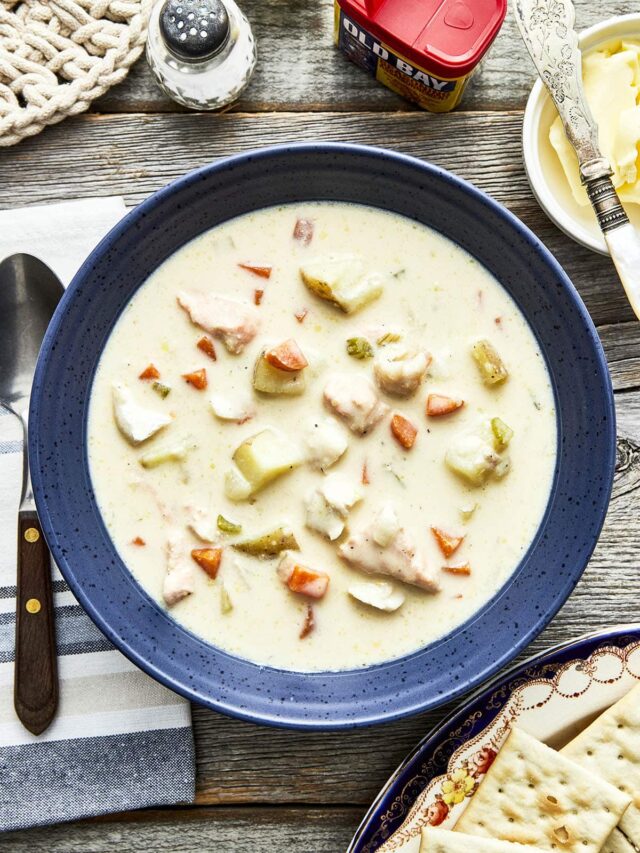 A bowl of East Coast fish chowder on a table with salt and pepper, butter, and Premium Plus crackers.