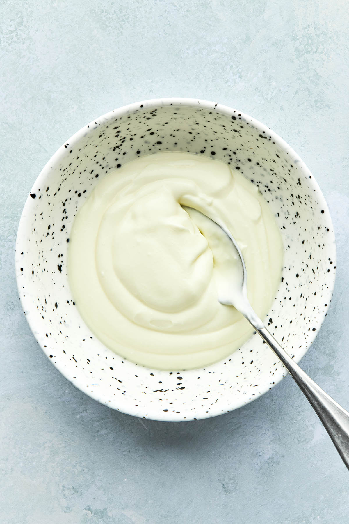 A bowl of crème fraîche with a spoon in the bowl.
