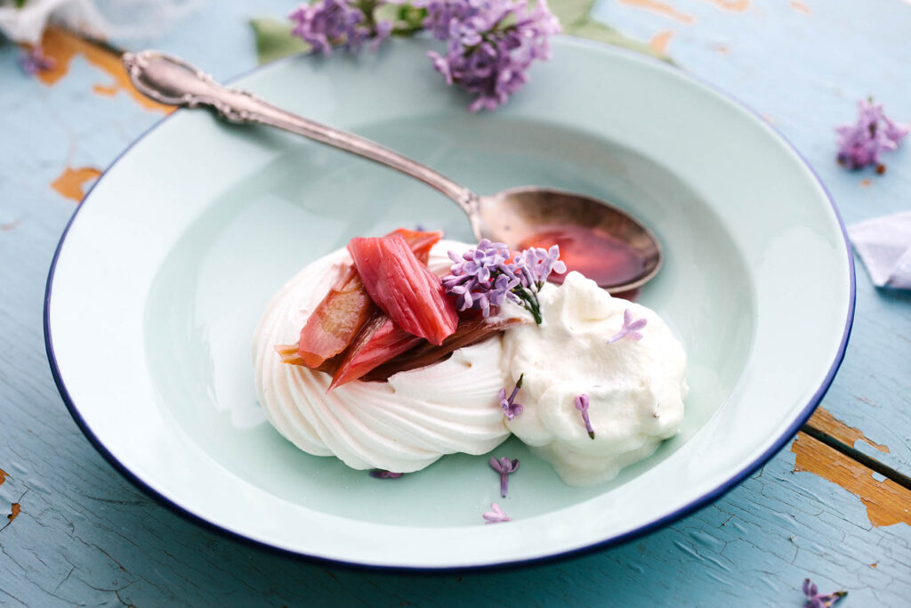 A small meringue topped with stewed rhubarb and lilac blossoms.