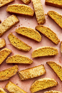 An arrangement of pumpkin biscotti on a blush-pink background.