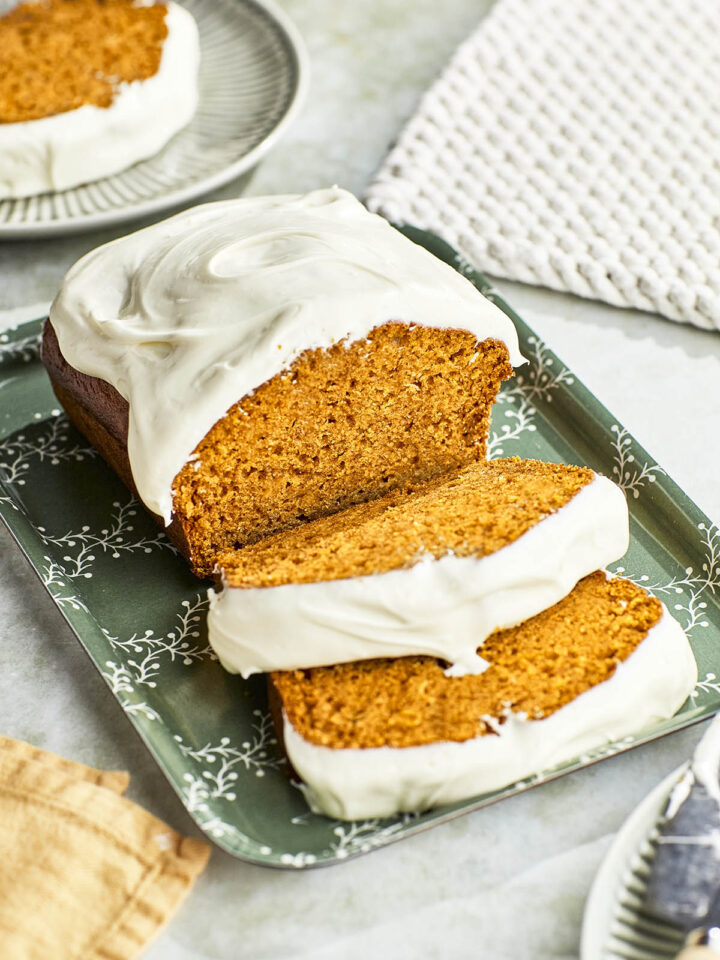 A 45° view of a sliced pumpkin loaf with cream cheese frosting.