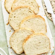 Slices of porridge bread on a terrazzo board with a bread knife nearby.