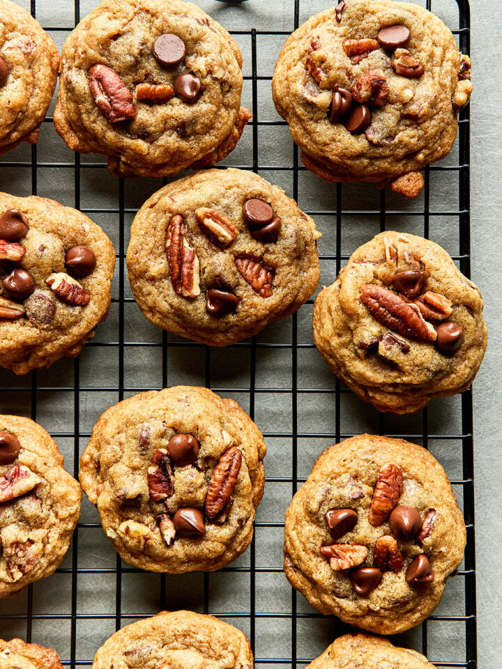 A batch of old-fashioned chocolate chip pecan cookies on a cooling rack.