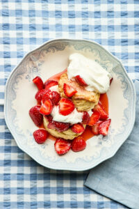 Classic strawberry shortcake in a blue and white bowl on a blue and white gingham tablecloth.