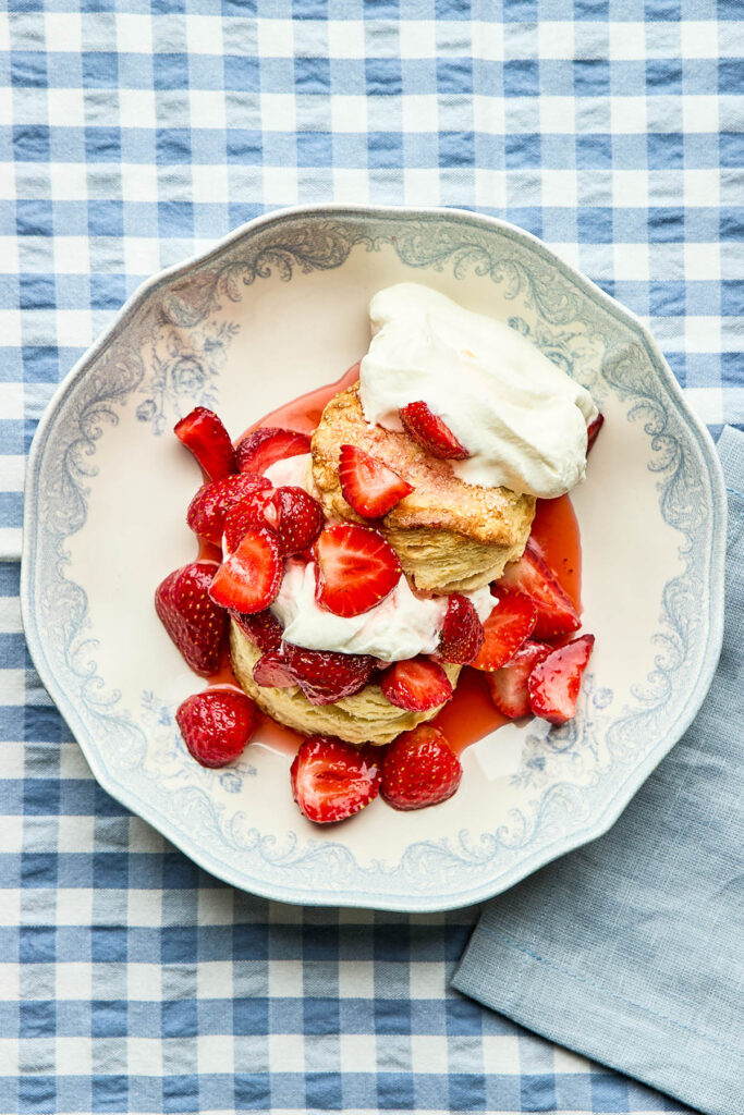 Classic strawberry shortcake in a blue and white bowl on a blue and white gingham tablecloth.