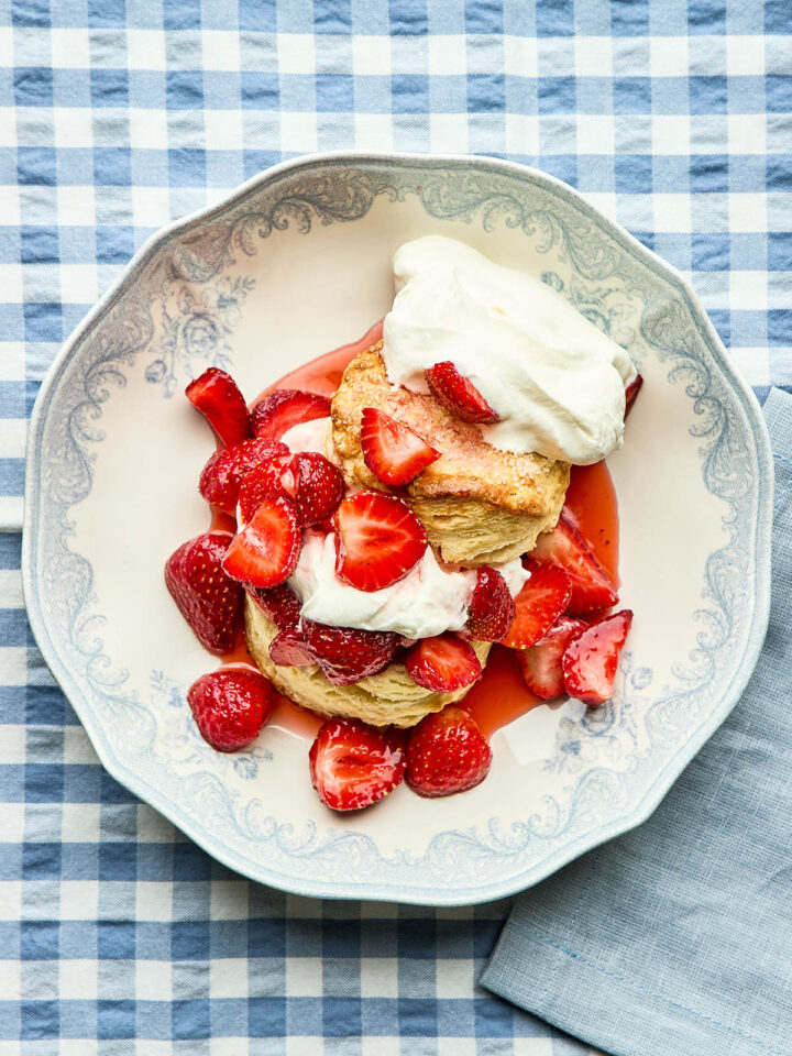 Classic strawberry shortcake in a blue and white bowl on a blue and white gingham tablecloth.