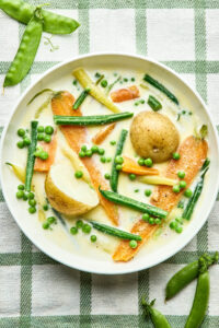 A bowl of Nova Scotia Hodge Podge on a green and white striped tablecloth