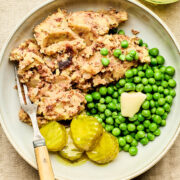 A bowl of Newfoundland-style corned beef hash with peas and mustard pickles on the side.