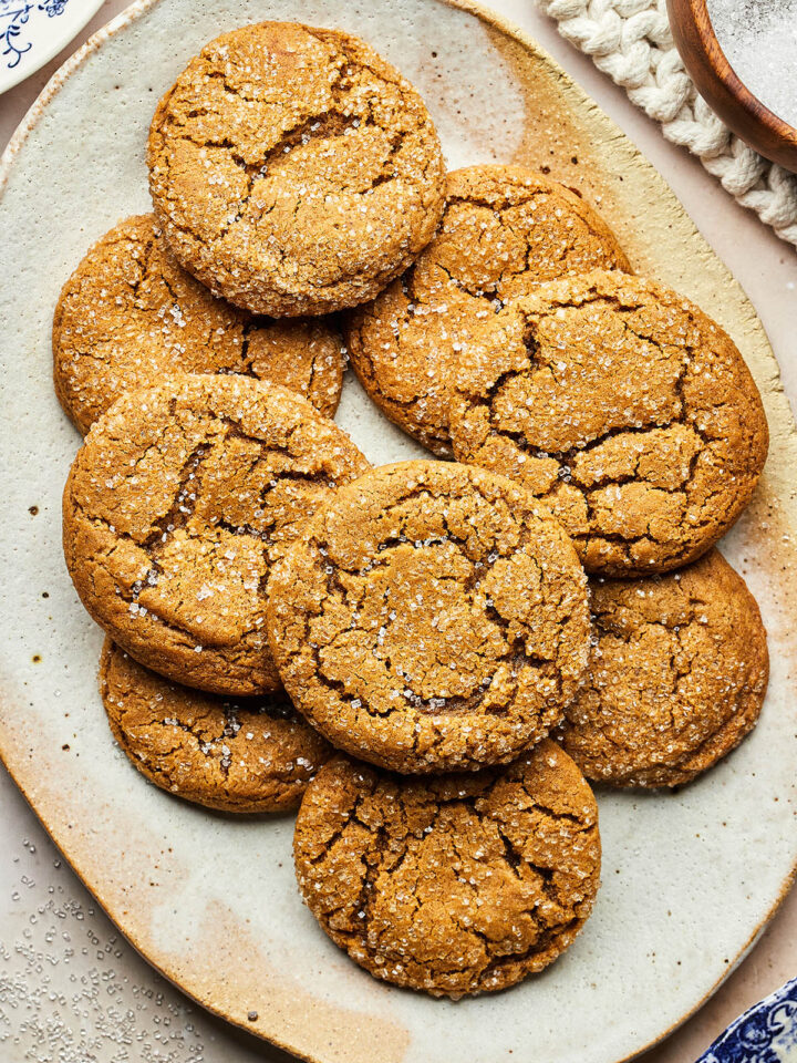 An oval platter of ginger sparklers wih a bowl of coarse sugar and small blue plates nearby.
