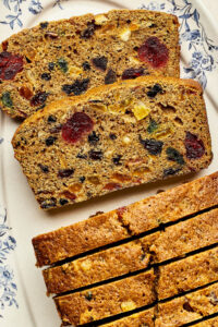 Slices of Christmas fruitcake with rum on a blue and white platter.