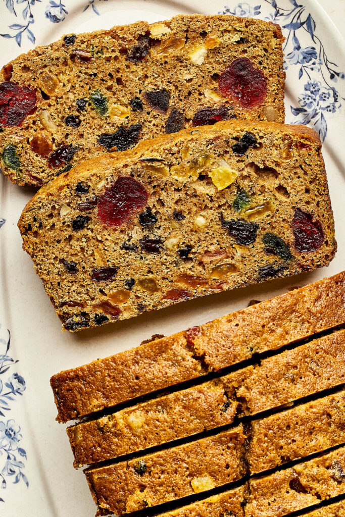 Slices of Christmas fruitcake with rum on a blue and white platter.