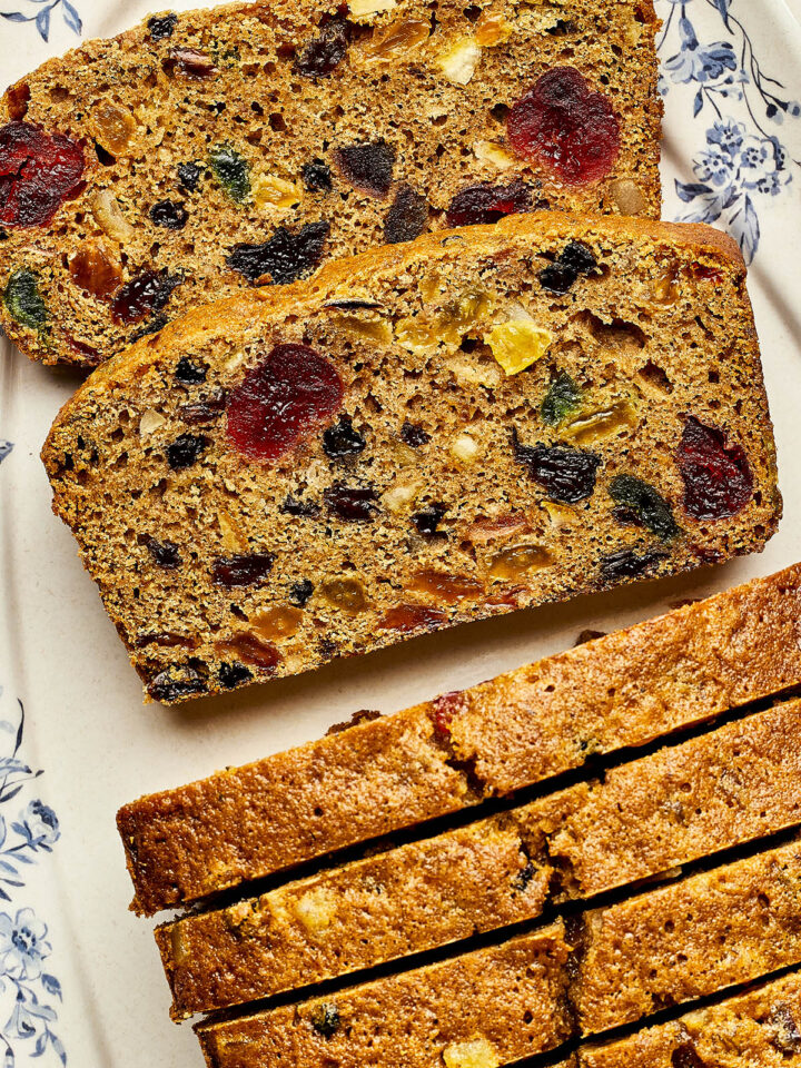 Slices of Christmas fruitcake with rum on a blue and white platter.