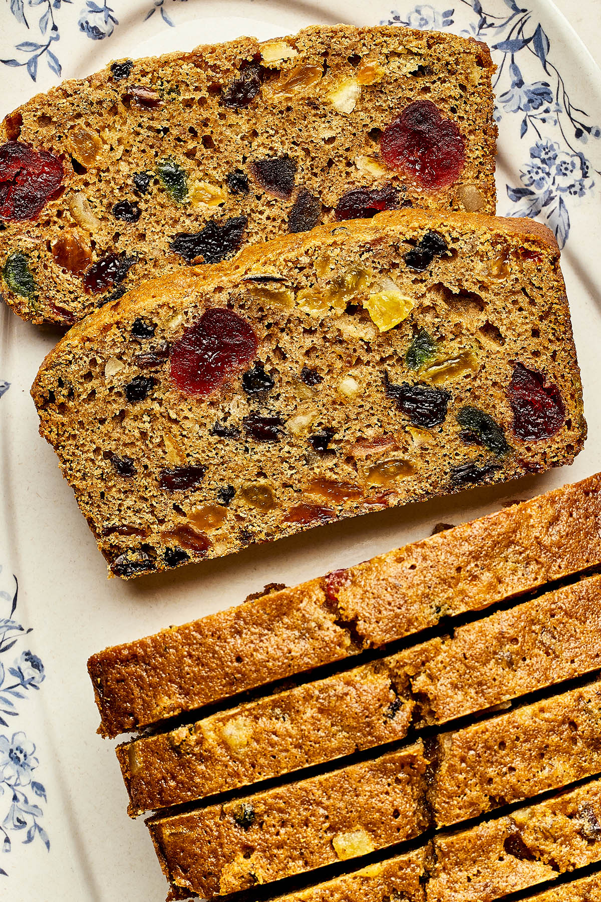 Slices of Christmas fruitcake with rum on a blue and white platter.