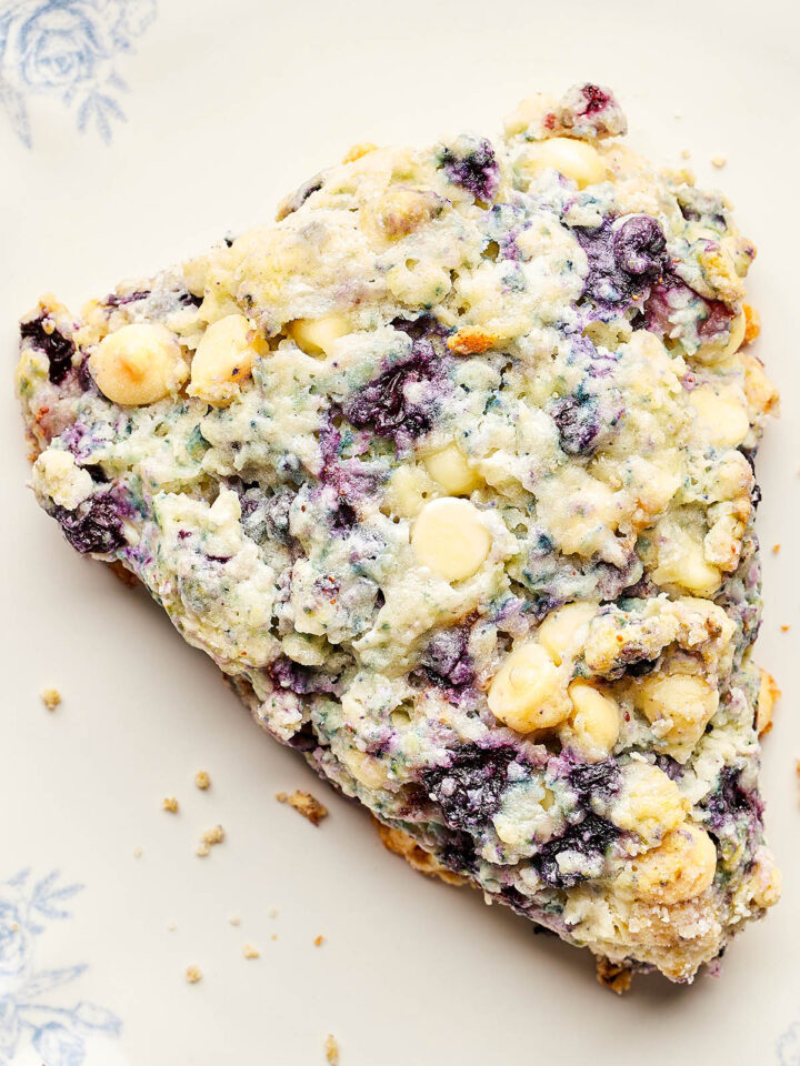 One out of a batch of blueberry white chocolate scones on a blue and white plate.
