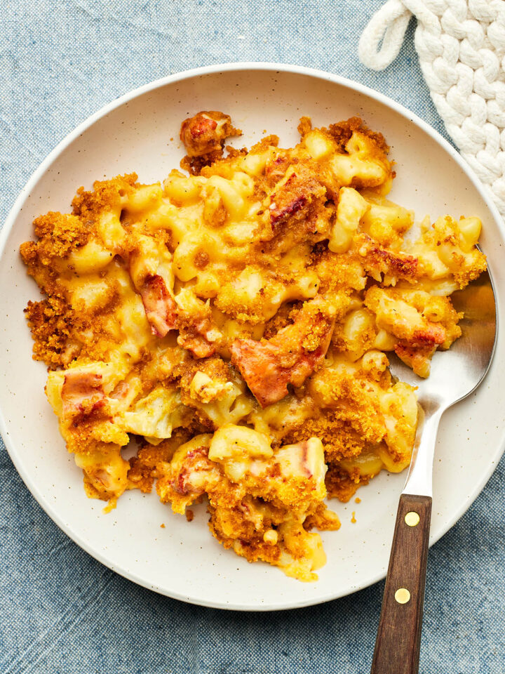 A bowl of lobster mac and cheese on a blue tablecloth.