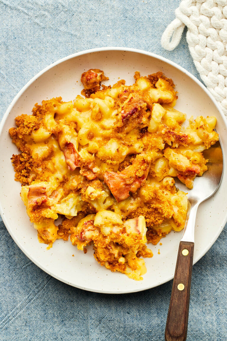 A bowl of lobster mac and cheese on a blue tablecloth.