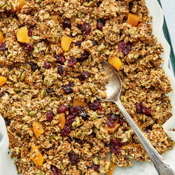 A batch of nut-free granola with honey with a serving spoon in the baking dish.
