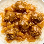 A bowl of sweet and sour beef meatballs with pineapple in a tangy sauce, served over basmati rice.